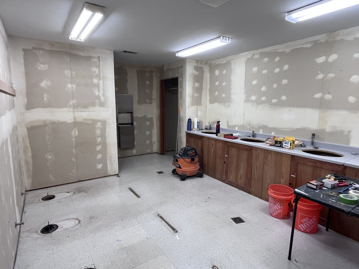 Commercial restroom in progress, with a wood vanity and patched walls